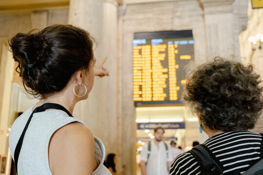 Woman pointing at departure board in Milan train station