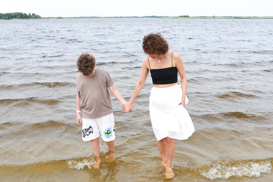 A mother and son are walking by the river.
