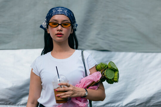 Young Woman With Sunglasses Holding Coffee And Lotus