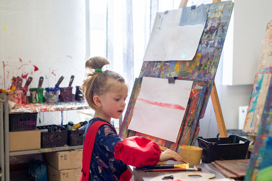 Little child draws on an easel in an art workshop