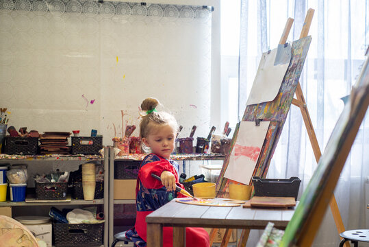 Little child draws on an easel in an art workshop