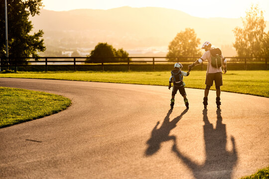 Father Holding Son's Hand While Roller Skating at Sunset
