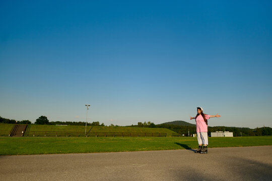 Woman Roller Skating with Arms Outstretched in Open Park