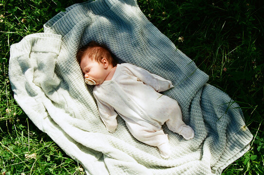 Baby sleeps on blanket in green grass