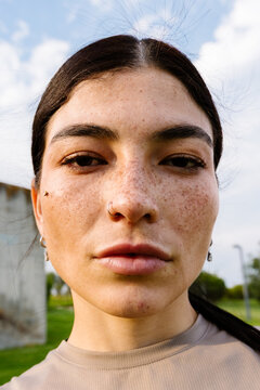 Headshot of relaxed Latina woman in sunny park