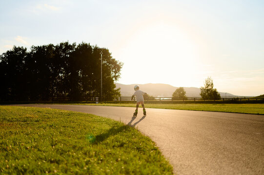 Little boy roller skating at sunset in the park