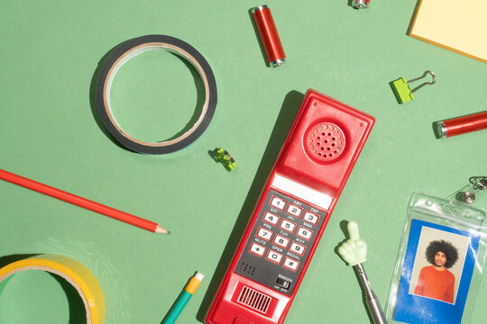 Retro red telephone with office accessories on green background