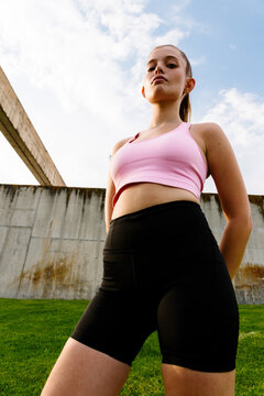 Low-angle portrait of an empowered female runner in a sunny city park