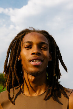 Close-up of smiling Black elite athlete with dreadlocks in sunny park