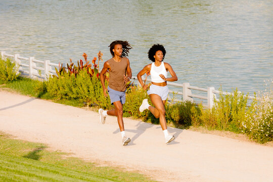 Active couple jogging together along a scenic park lake