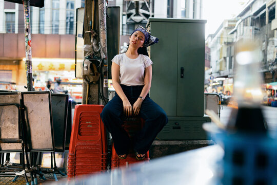 Young Woman Sitting on Stools in Urban Street