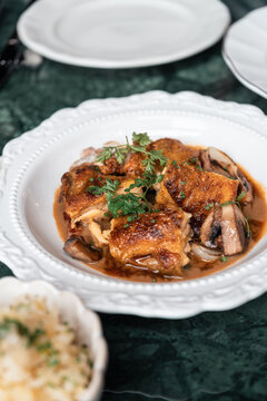 Roast Chicken Dish Served With Mushrooms and Herbs on a White Plate