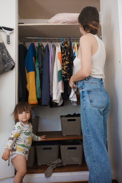Child and Adult Sorting Clothes in a Closet at Home