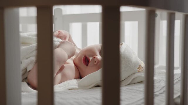 Newborn baby rests peacefully in crib, gazing upwards with innocent curiosity, creating a serene and heartwarming scene. Crib showing care love and peaceful family warmth