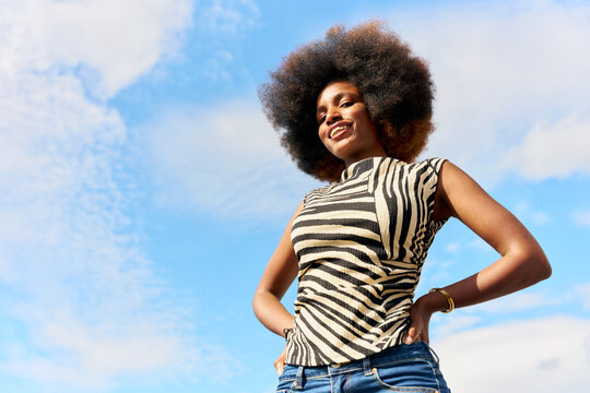 Woman With Curly Hair Smiles Outdoors Under Blue Sky