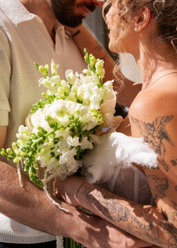 Bride and groom holding white and green wedding bouquet together