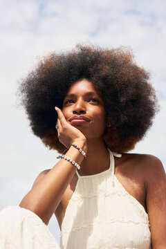 Optimistic Woman With Curly Hair Sitting and Thinking Outdoors