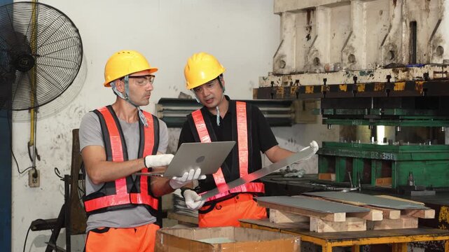 Morning sheet metal inspection stops briefly while the technicians check that shift's production figures on an open laptop screen