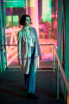 Young Woman Walks Through Colorful Light Display in Urban Space
