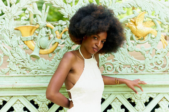 Woman Poses Near Ornate Garden Gate With Details of Nature