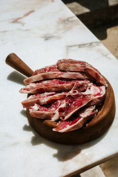 Cuts of Meat on a Wooden Platter in a Sunlit Kitchen
