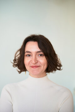 Woman Smiling in a White Sweater Against a Plain Background
