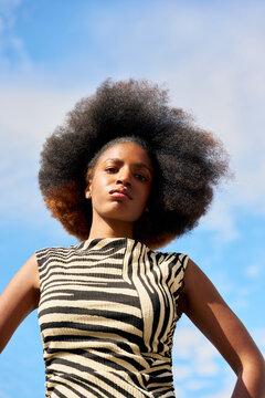 Strong Woman Poses Outdoors Wearing a Striped Outfit Under Blue Sky