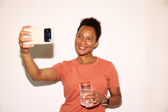 Woman takes selfies with a glass of water
