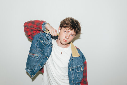 Young man putting on denim jacket 