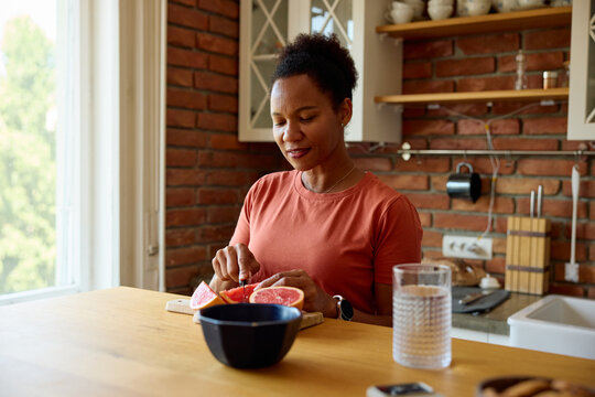 Woman chops grapefruit in the kitchen