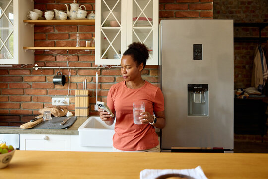A woman stands by the fridge in the kitchen