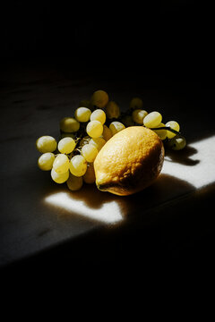 Grapes and Lemon Placed on a Table With Soft Light Falling