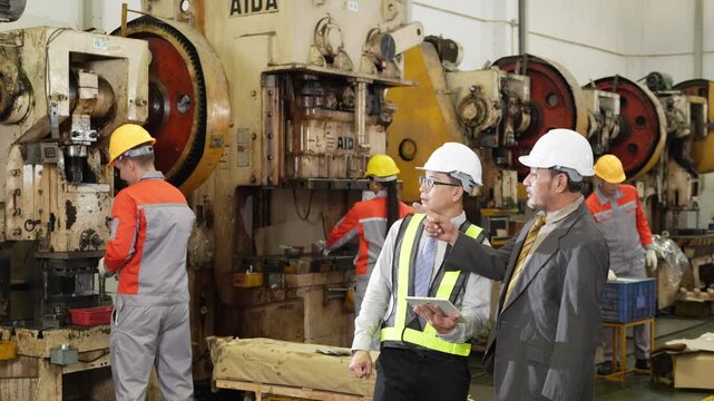 Audit walkthrough of the factory puts a supervisor and a manager together over a tablet before the stamping press line