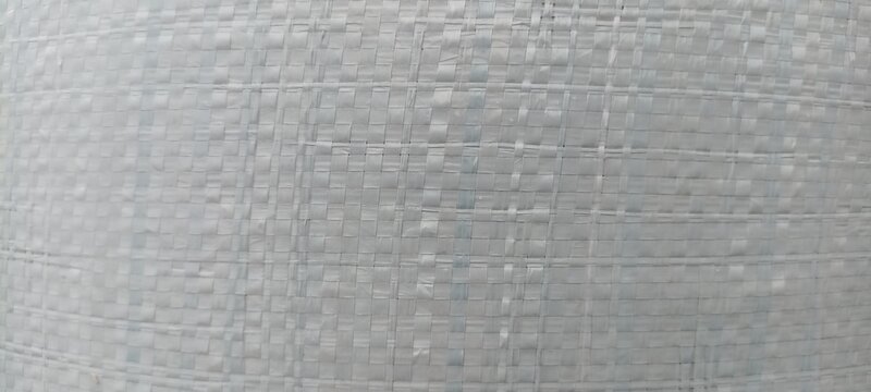 Woven plastic texture showing white grid pattern, ideal for packaging mockups, industrial fabric backgrounds, supply chain graphics, and material design