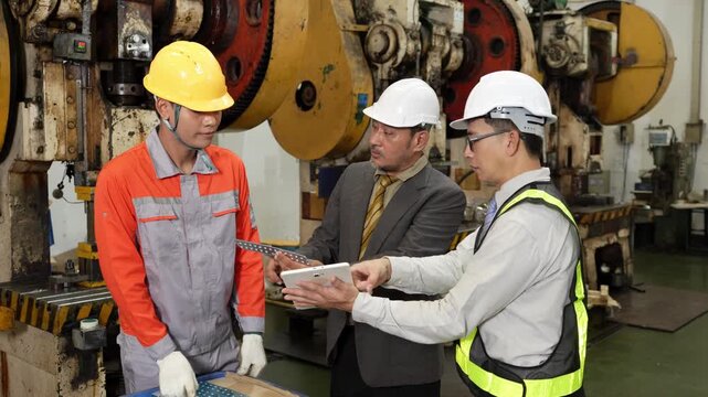 Factory audit talk settles onto a freshly stamped metal part that passes between three men on the busy shop floor