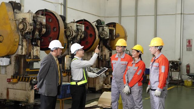 Audit clipboard on the factory floor moves along the stamping line with a tablet held open beside it by five people