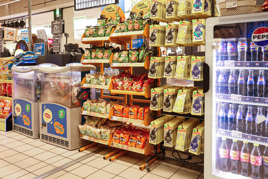 Warsaw, Poland, 20 August 2026. Shoppers viewing a wide selection of chips, candy, drinks, and car air fresheners near checkout