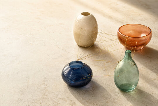 Minimalist ceramic and glass vases on stone surface. Modern pottery collection with string connections. Elegant home decor still life.