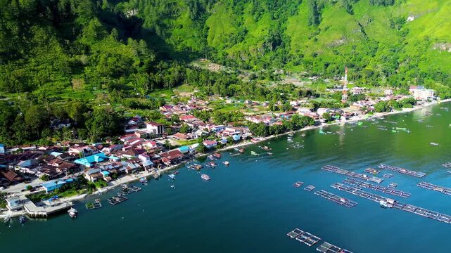 Scenic aerial view of Lake Toba lakeside village surrounded by green mountains in Indonesia