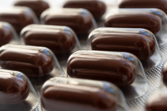 Brown gel pills, dark red capsules close up
