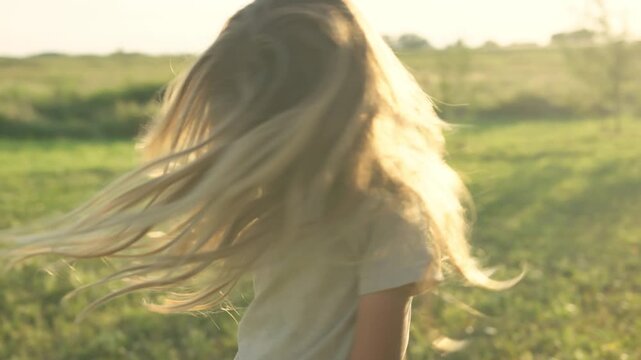 Boy looking up at sky with eyes closed in golden backlit field at sunset