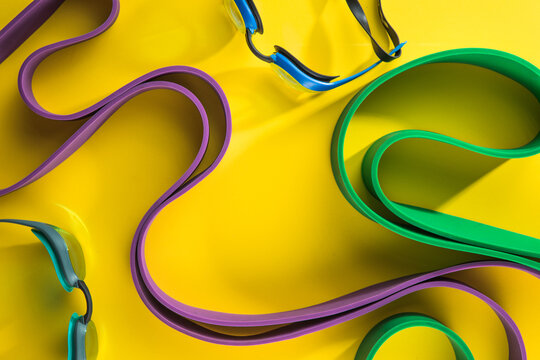Set of sports swim  accessories, fitness bands on yellow background top view.