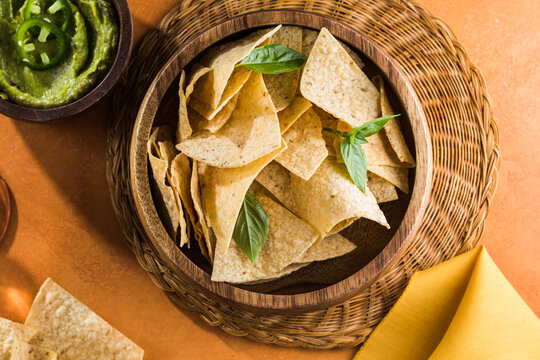 A plate of delicious tortilla nachos  jalapeno peppers, red salsa and guacamole dip.