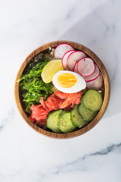 Overhead view of a colorful vegan poke bowl with rice, egg, gimnger, seaweed, radish, and veggies