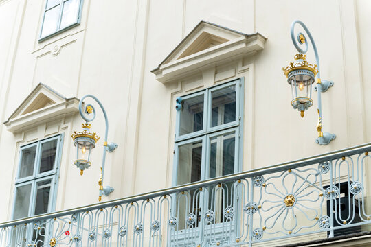 Neoclassical ancient European architecture. Wall lamp lantern on balcony architecture. Elegant wall lamp in classicism or baroque style. Gilded decorative details and metal balcony railing