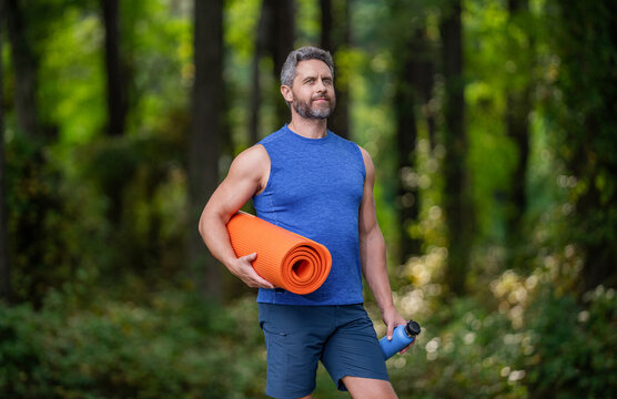 Yoga coach. Sport man ready for workout. Healthy lifestyle. Fitness and sport. Yoga mat for training. Sportsman in forest. Man in sportswear with fitness mat. Fit your body. In harmony with nature