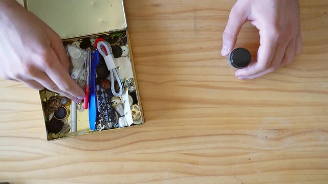 Vintage labours concept. Top view shot of Hands going through Sewing Kit in old metal box