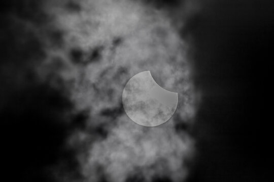 Partial solar eclipse viewed through dark dramatic clouds in Diyarbakir, Turkey.