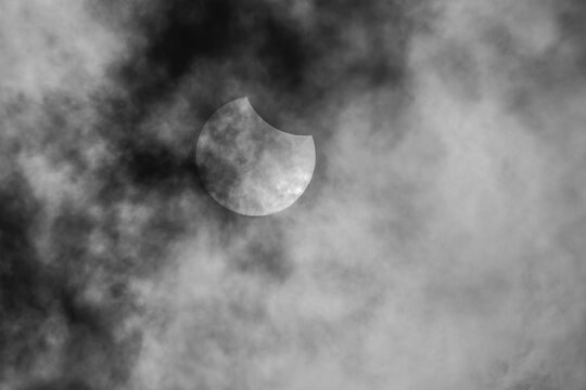 Partial solar eclipse viewed through dark dramatic clouds in Diyarbakir, Turkey.