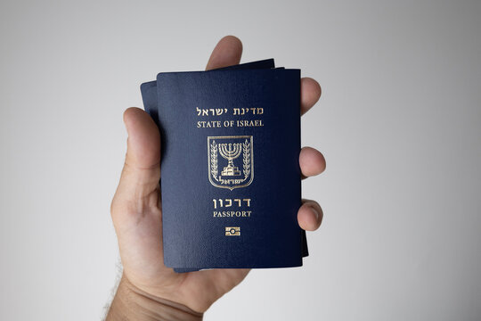 Hand holding multiple Israeli passports (Darkon) on a neutral background